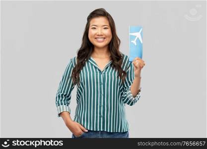 travel, tourism and vacation concept - happy smiling young asian woman with air ticket and passport over grey background. happy asian woman with air ticket and passport