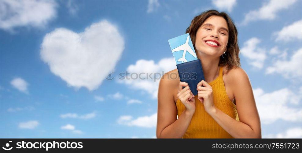 travel, tourism and vacation concept - happy smiling young woman in mustard yellow top with air ticket and passport over blue sky and clouds background. happy young woman with air ticket and passport