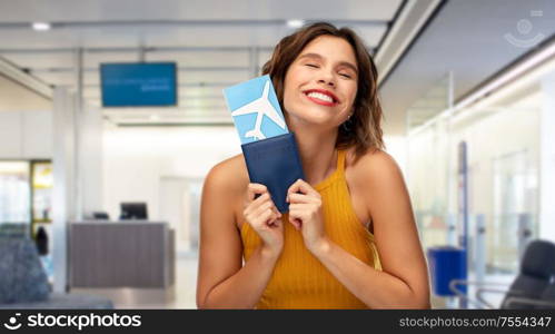 travel, tourism and vacation concept - happy smiling young woman in yellow top with air ticket and passport over airport lounge background. happy young woman with air ticket at airport