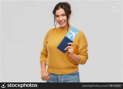 travel, tourism and vacation concept - happy smiling young woman with air ticket and passport over grey background. happy young woman with air ticket and passport