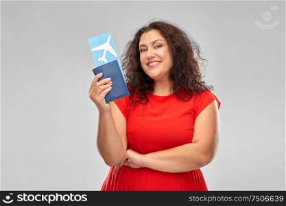 travel, tourism and vacation concept - happy woman in red dress with passport and air ticket over grey background. happy woman with passport and air ticket