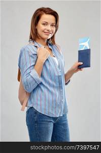 travel, tourism and vacation concept - happy woman with air ticket, passport and backpack over grey background. happy woman with air ticket, passport and bacjpack