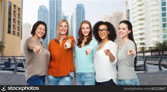 travel, tourism, choice, diverse and people concept - group of happy plus size women in casual clothes pointing finger on you over dubai city street background