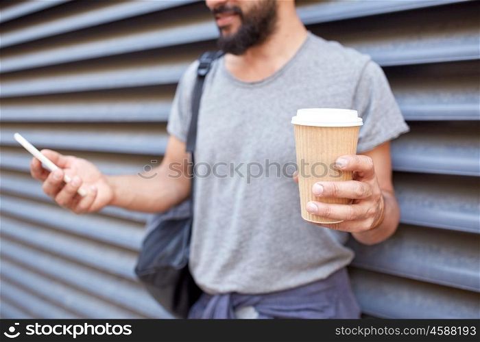 travel, tourism, communication, technology and people concept - close up of man with backpack and coffee cup texting on smartphone on city street