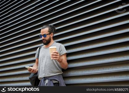 travel, tourism, communication, technology and people concept - man with backpack and coffee cup texting on smartphone on city street