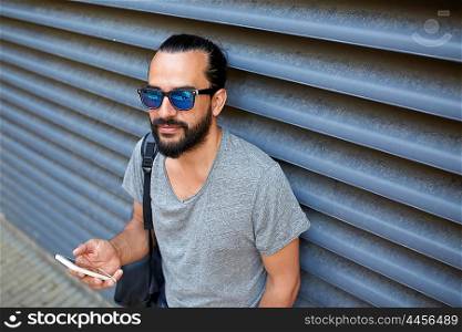 travel, tourism, communication, technology and people concept - man with backpack texting on smartphone on city street
