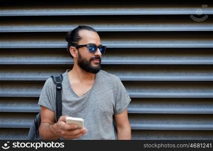 travel, tourism, communication, technology and people concept - man with backpack texting on smartphone on city street