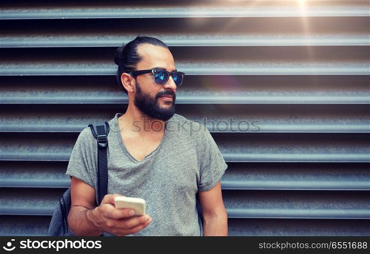 travel, tourism, communication, technology and people concept - man with backpack texting on smartphone on city street. man with backpack texting on smartphone in city. man with backpack texting on smartphone in city