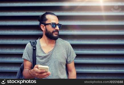 travel, tourism, communication, technology and people concept - man with backpack texting on smartphone on city street. man with backpack texting on smartphone in city. man with backpack texting on smartphone in city