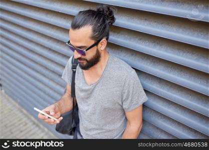 travel, tourism, communication, technology and people concept - man with bag texting on smartphone on city street