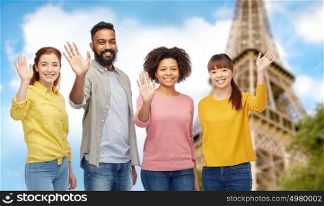 travel, tourism, diversity and people concept - international group of happy smiling men and women waving hands over eiffel tower background. international group of happy people waving hands