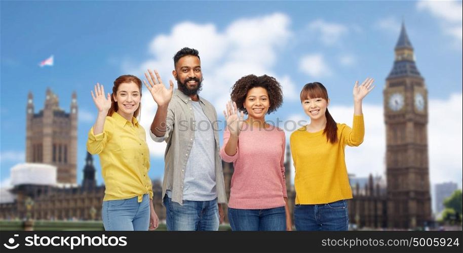 travel, tourism, diversity and people concept - international group of happy smiling men and women waving hands over london city background. international group of happy people waving hands