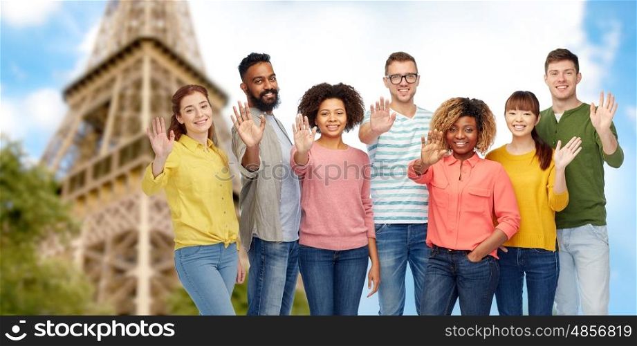 travel, tourism, diversity, ethnicity and people concept - international group of happy smiling men and women waving hand over eiffel tower background