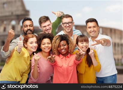 travel, tourism, diversity, ethnicity and people concept - international group of happy smiling men and women showing thumbs up and peace over coliseum background