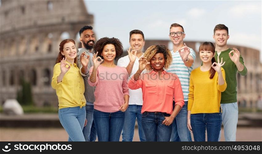 travel, tourism, diversity, ethnicity and people concept - international group of happy smiling men and women showing ok hand sign over coliseum background. international people showing ok over coliseum