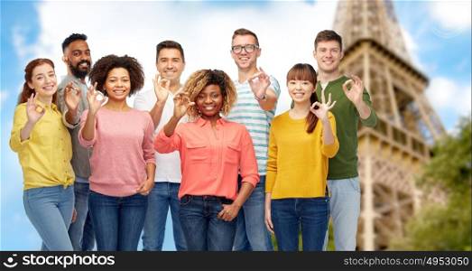 travel, tourism, diversity, ethnicity and people concept - international group of happy smiling men and women showing ok hand sign over eiffel tower background. international people showing ok over eiffel tower