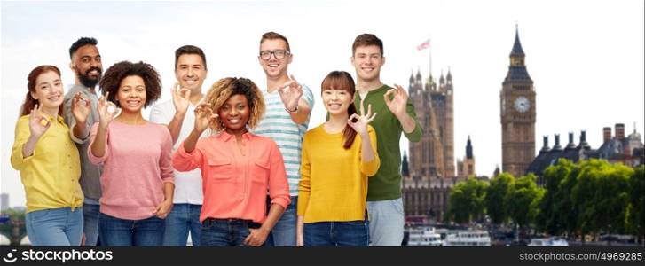 travel, tourism, diversity, ethnicity and people concept - international group of happy smiling men and women showing ok hand sign over london city background. international group of people showing ok in london