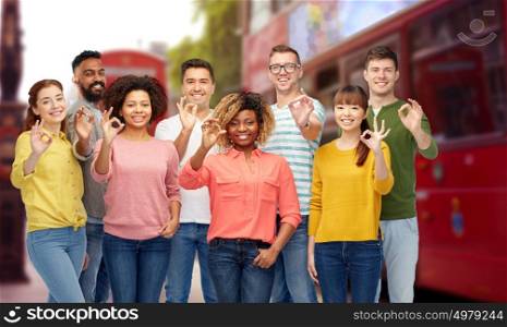 travel, tourism, diversity, ethnicity and people concept - international group of happy smiling men and women showing ok hand sign over london city street background. international group of people showing ok in london