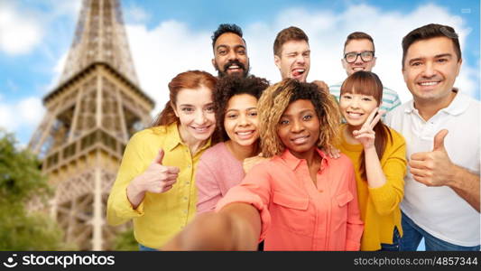 travel, tourism, diversity, technology and people concept - international group of happy smiling men and women taking selfie over eiffel tower background