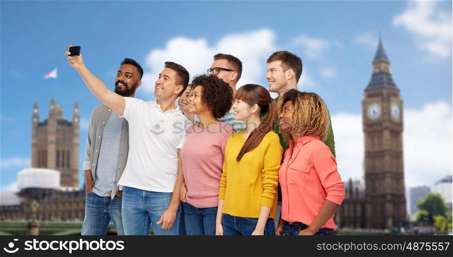 travel, tourism, diversity, technology and people concept - international group of happy smiling men and women taking selfie by smartphone over london city background
