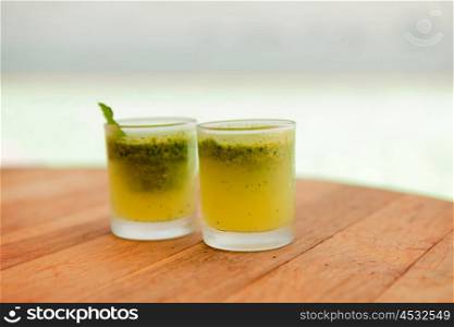 travel, tourism, drinks and food concept - glasses of fresh juice or cocktail on table at beach