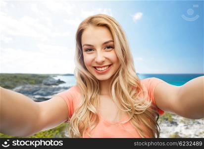 travel, tourism, emotions, expressions and people concept - happy smiling young woman taking selfie over exotic tropical beach background