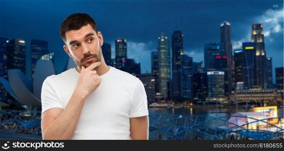 travel, tourism, expression and people concept - man thinking over night singapore city background