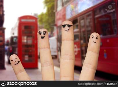 travel, tourism, family, people and body parts concept - close up of four fingers with smiley faces over london city street and red bus background