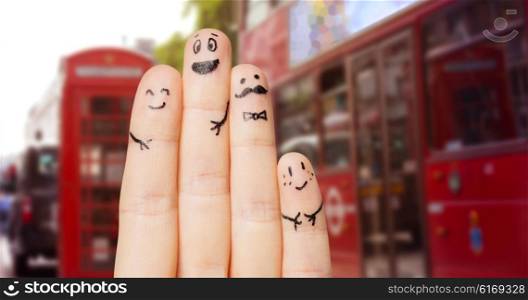 travel, tourism, family, people and body parts concept - close up of four fingers with smiley faces over london city street and red bus background