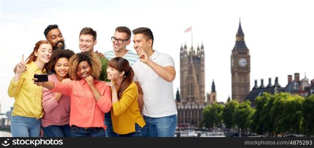 travel, tourism, friendship, technology and people concept - international group of happy smiling men and women taking selfie by smartphone over london city and big ben tower background