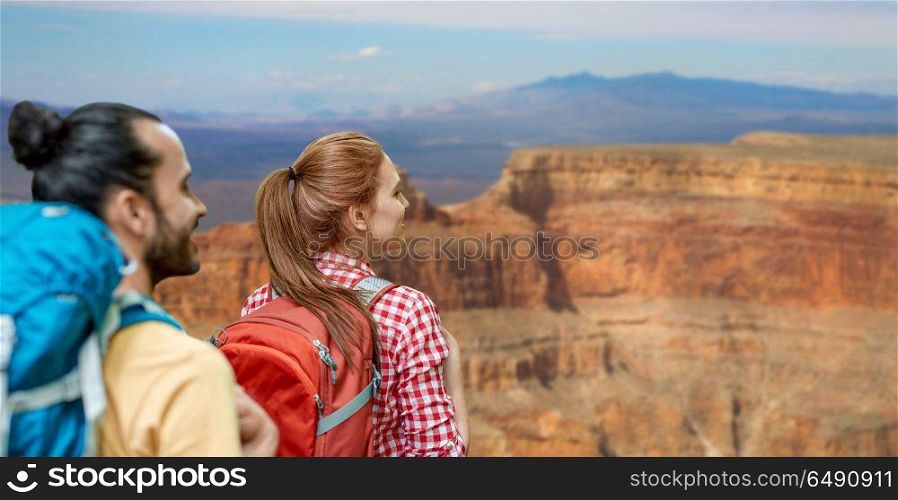 travel, tourism, hike and adventure concept - couple of travelers with backpacks over grand canyon national park background. couple with backpacks over grand canyon. couple with backpacks over grand canyon