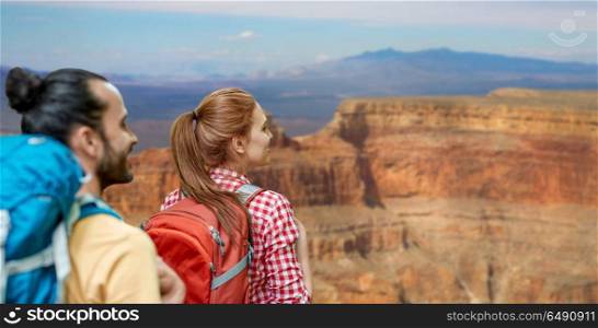 travel, tourism, hike and adventure concept - couple of travelers with backpacks over grand canyon national park background. couple with backpacks over grand canyon. couple with backpacks over grand canyon