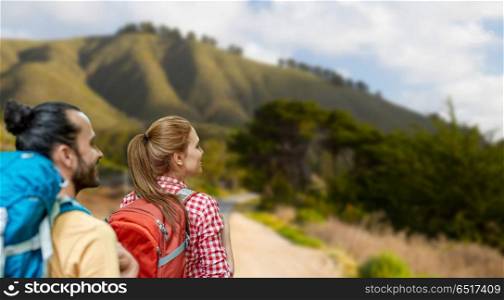 travel, tourism, hike and adventure concept - couple of travelers with backpacks over big sur hills of california background. couple with backpacks over big sur hills. couple with backpacks over big sur hills