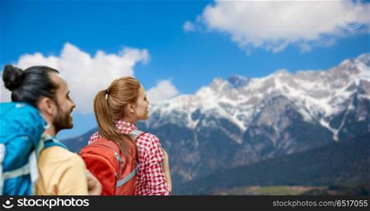 travel, tourism, hike and adventure concept - couple of travelers with backpacks over alps mountains background. couple with backpacks over alps mountains. couple with backpacks over alps mountains