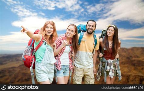 travel, tourism, hike and adventure concept - group of smiling friends with backpacks pointing finger to something over grand canyon national park hills background. group of friends with backpacks at grand canyon. group of friends with backpacks at grand canyon