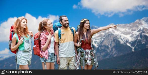 travel, tourism, hike and adventure concept - group of smiling friends with backpacks pointing finger to something over alps mountains background. group of friends with backpacks over mountains. group of friends with backpacks over mountains