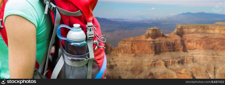 travel, tourism, hike and people concept - close up of woman with water bottle in backpack pocket over grand canyon national park background. close up of woman with water bottle in backpack. close up of woman with water bottle in backpack
