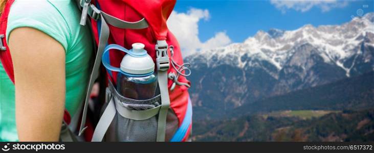 travel, tourism, hike and people concept - close up of woman with water bottle in backpack pocket over alps mountains background. close up of woman with water bottle in backpack. close up of woman with water bottle in backpack