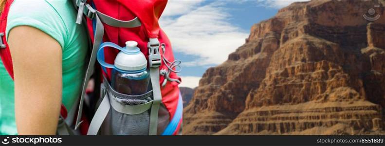 travel, tourism, hike and people concept - close up of woman with water bottle in backpack pocket over grand canyon national park background. close up of woman with water bottle in backpack. close up of woman with water bottle in backpack