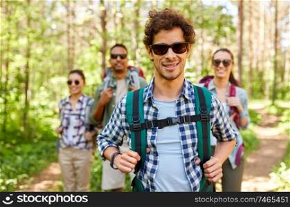 travel, tourism, hike and people concept - group of friends with backpacks in forest. friends with backpacks on hike in forest