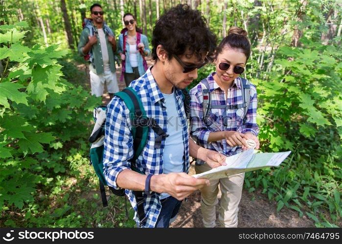 travel, tourism, hike and people concept - group of friends with map and backpacks in forest. friends with map and backpacks hiking in forest