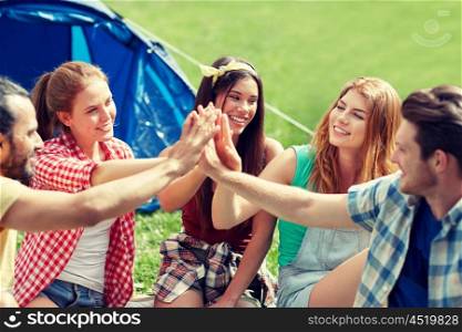 travel, tourism, hike and people concept - group of happy friends with tent making high five at camping