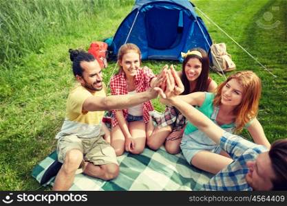 travel, tourism, hike and people concept - group of happy friends with tent making high five at camping