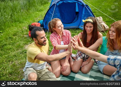 travel, tourism, hike and people concept - group of happy friends with tent making high five at camping