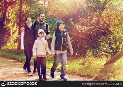 travel, tourism, hike and people concept - happy family walking with backpacks along road in woods. happy family with backpacks hiking in woods