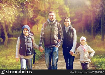 travel, tourism, hike and people concept - happy family walking with backpacks in woods. happy family with backpacks hiking