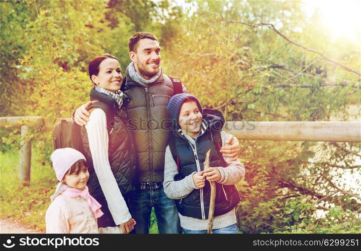 travel, tourism, hike and people concept - happy family with backpacks hiking in woods. happy family with backpacks hiking