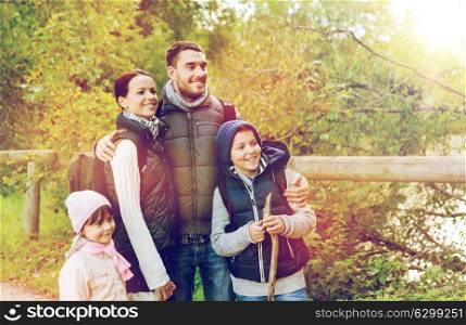 travel, tourism, hike and people concept - happy family with backpacks hiking in woods. happy family with backpacks hiking
