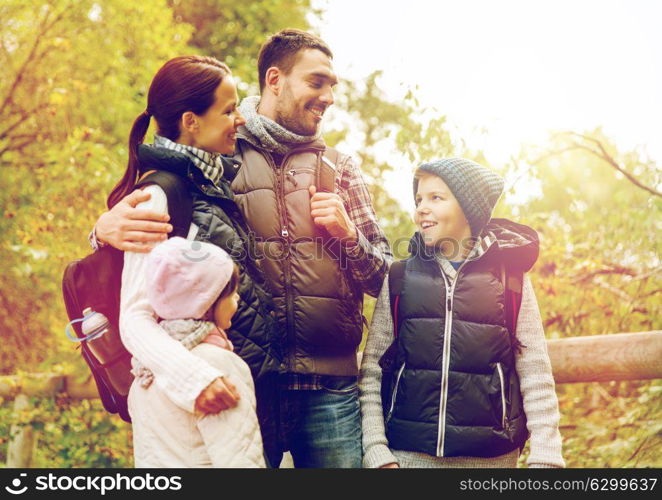 travel, tourism, hike and people concept - happy family with backpacks hiking in woods. happy family with backpacks hiking