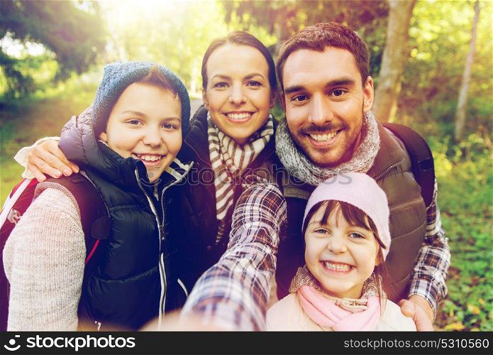 travel, tourism, hike and people concept - happy family with backpacks taking selfie and hiking. family with backpacks taking selfie and hiking